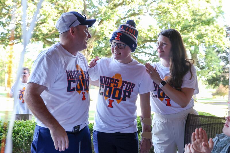 Cooper Freedlund, 13, center, stands with his parents, Gary, left, and Jamie Freedlund, all of Bourbonnais, after ringing a bell during a party celebrating the end of his chemotherapy on June 28, 2025. The Freedlunds run Mattea's Joy, a nonprofit that supports families with hospitalized children which they started in honor of their late daughter, Mattea.
