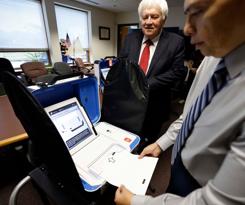 Kane County Clerk John Cunningham, left, and Director Of Elections at Kane County Clerk's Office Raymond Esquivel, demonstrate how the new voting machines work while setting up for early voting machines Tuesday, Sept. 24, 2024 in Geneva.