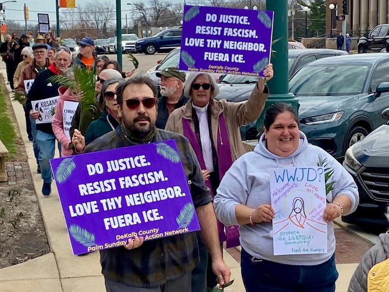 Participants hold signs during a procession at a Palm Sunday Faith Action event on Sunday, March 29, 2026, in front of the DeKalb County Courthouse in Sycamore. Area Christian ministers organized the event to combat the rise of Christian nationalism in the U.S.
