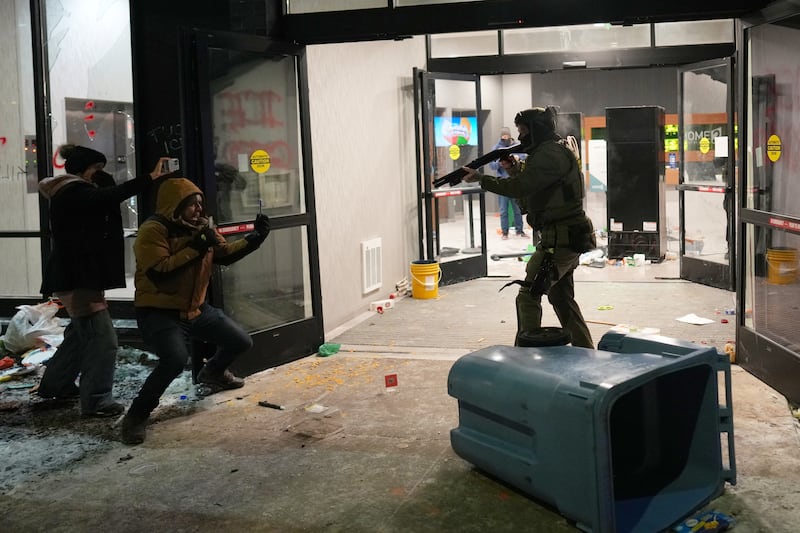 A federal agent points a weapon at a person outside a hotel during a noise demonstration protest in response to federal immigration enforcement operations in the city Sunday, Jan. 25, 2026, in Minneapolis. (AP Photo/Adam Gray)