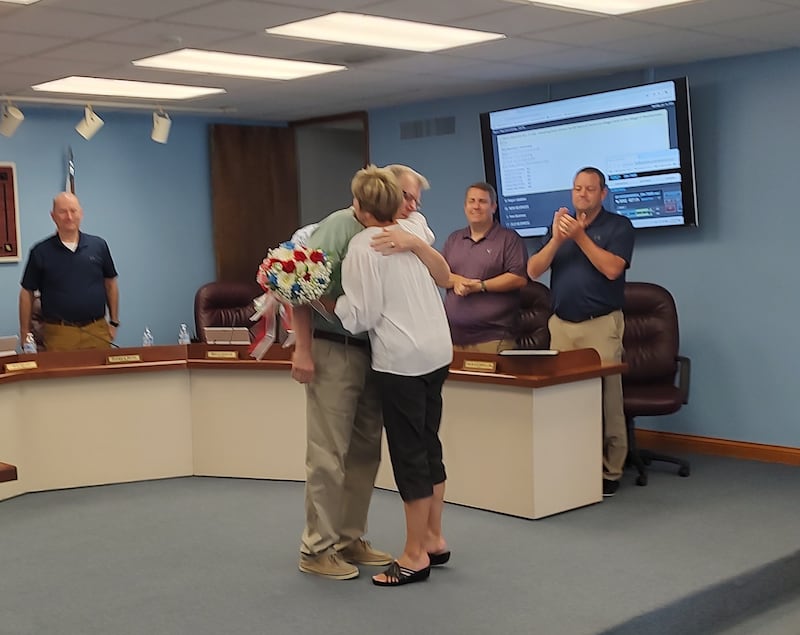 Bourbonnais Clerk Brian Simeur gets a hug from his wife, Denise, during Monday's board meeting. Simeur gave his wife a bouquet of flowers.