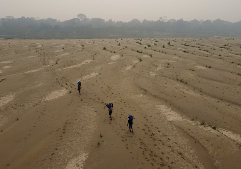FILE - Residents transport drinking water from Humaita to the Paraizinho community, along the dry Madeira River, a tributary of the Amazon River, during the dry season, Amazonas state, Brazil, Sept. 8, 2024. (AP Photo/Edmar Barros, File)