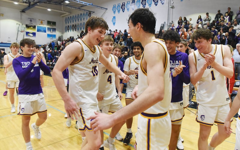 Downers Grove North players including Bobby Grganto, left, and Aidan Akkawi, right, clebrate the Trojans’ 52-45 victory over West Aurora during the Class 4A Downers Grove South regional final on Friday, Feb. 28, 2025 in Downers Grove.