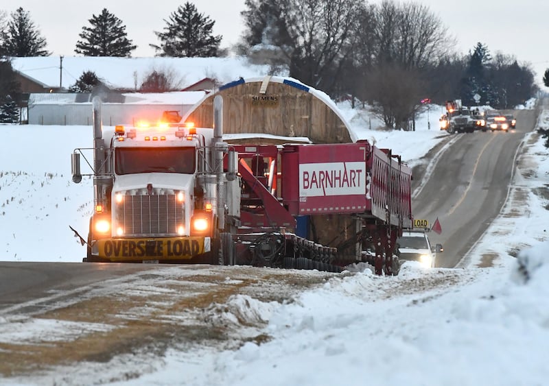 Two semi tractors pulling and pushing the trailer carrying a large turbine for Constellation's Byron generating station head north on German Church Road en route to the nuclear power plant on Monday, Dec. 8, 2025.