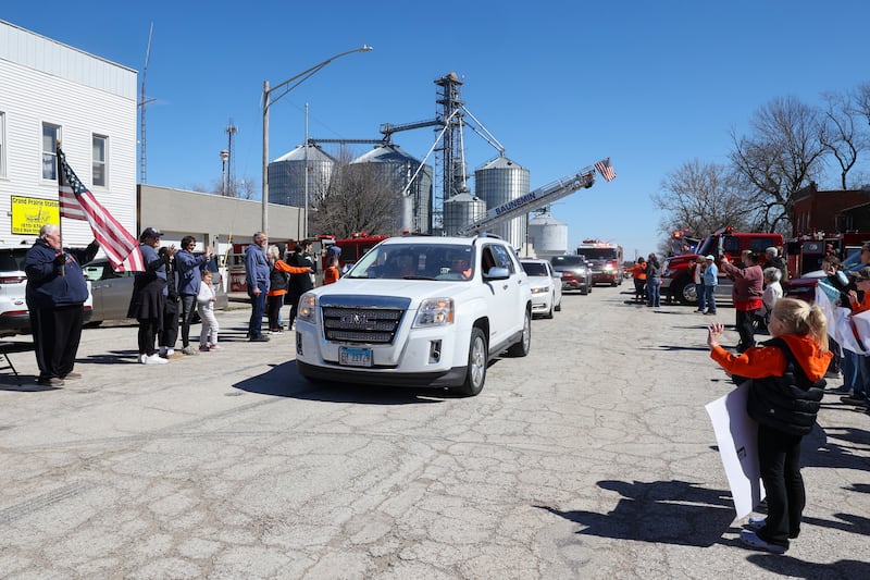 Willy VanWassenhove, seated in the front passenger seat, is greeted by friends, family and numerous rural fire departments along Main Street in Cabery upon his return home to the area on Saturday, March 22, 2025. VanWassenhove hasn't been home since September 20 when his hayrack was struck on the side of the road, leaving him seriously injured.