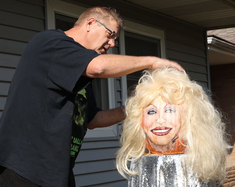 John Kettman of La Salle, prepares his Dolly Parton pumpkin on Thursday, Oct. 29, 2026 outside his home in La Salle. Kettman has been painting faces on pumpkins since 2015. "I apply my art and talent in everyting I do," said Kettman. Kettman calls his pumpkin the "Dazzling Dolly the Gorgeous Gourd."