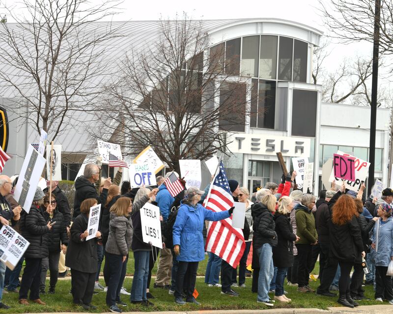 Community members line Ogden Ave. holding signs and flags near the Tesla dealership on Saturday April 5, 2025, in Lisle during the Hands Off Demonstration.
