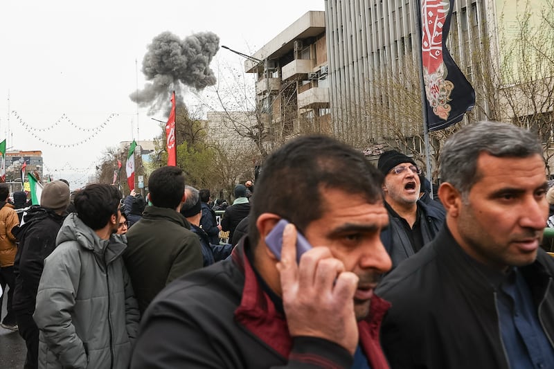 Smoke from an explosion rises behind demonstrators attending the annual anti-Israeli Quds Day, or Jerusalem Day, rally in support of Palestinians in Tehran, Iran, Friday, March 13, 2026. (Mohammad Mahdi Dehghani/Fars News Agency via AP)