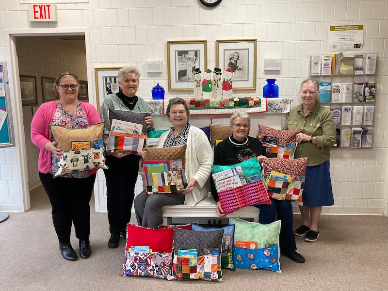Members of the Covered Bridge Quilters Guild display some of the reading pillows they crafted to benefit children sheltered by Freedom House in Princeton