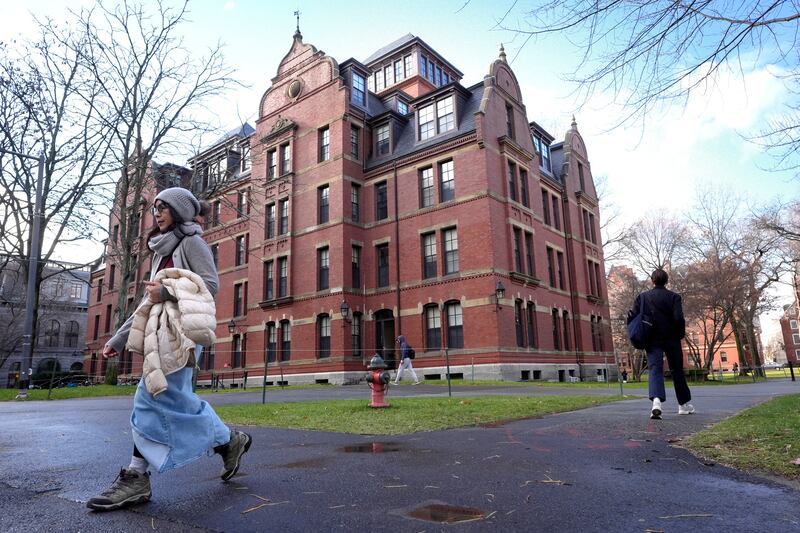 FILE - People walk between buildings, Dec. 17, 2024, on the campus of Harvard University in Cambridge, Mass. (AP Photo/Steven Senne, File)