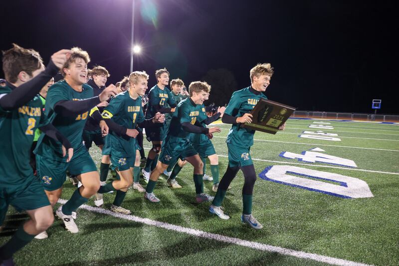 Coal City’s Dane Noffsinger carries the IHSA Class 1A Maroa-Forsyth Super-Sectional championship plaque as the team runs to celebrate with the fan section during the Coalers’ 1-0 victory over Williamsville on Monday, Nov. 3, 2025.