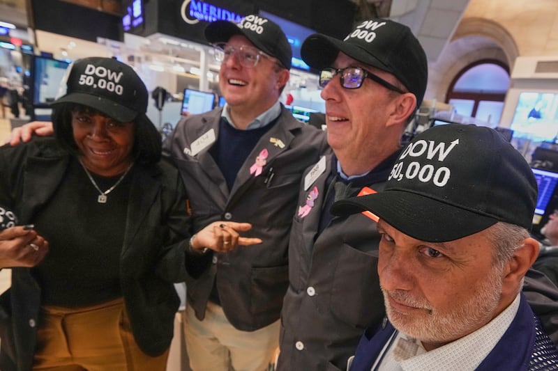 Trader Joel Lucchese, right, and colleagues wear "DOW 50,000" caps on the floor of the New York Stock Exchange as the Dow Jones industrial average intra-day number topped the 50,000 level for the first time, Friday, Feb. 6, 2026. (AP Photo/Richard Drew)