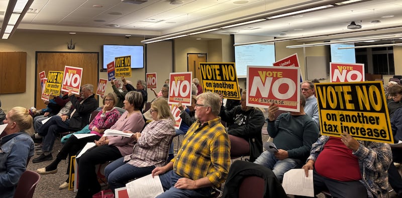 Attendees hold up vote no signs at the McHenry County Board budget and levy vote Nov. 19. 2024.