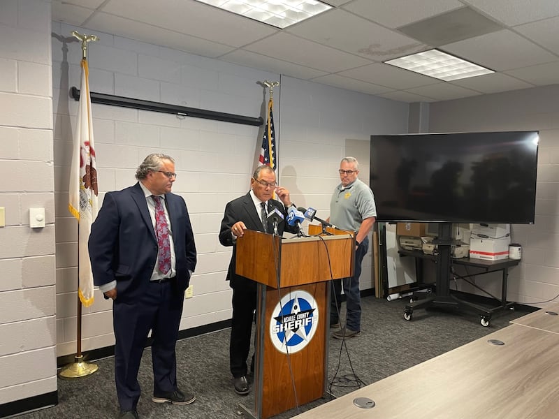 Investigators prepare Friday, July 18, 2025, to discuss the case against Ronald W. Martin Jr., who has been charged with murder for the two fatal shootings in rural Sheridan. La Salle County State's Attorney Joe Navarro (at podium) is flanked by assistant Greg Sticka (left) and Undersheriff David Ortiz (right).