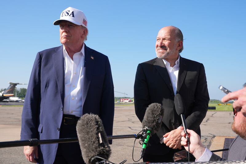 President Donald Trump, left, listens as Commerce Secretary Howard Lutnick speaks with reporters before boarding Air Force One at Morristown Municipal Airport in Morristown, N.J., Sunday, July 6, 2025, en route to Washington. (AP Photo/Jacquelyn Martin)