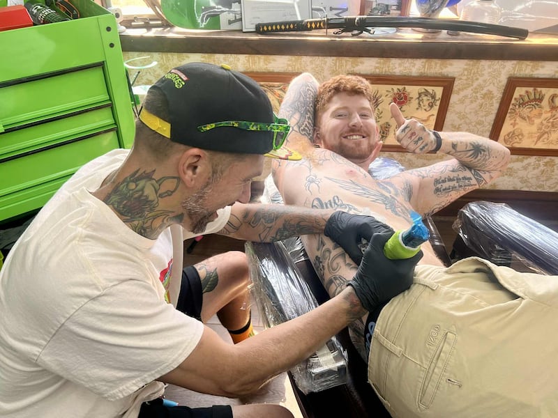 Owner Jacob Mekeel adds some ink to his apprentice, Brandon Kilday, at Merlo Macs Tatt Shack in Dixon.