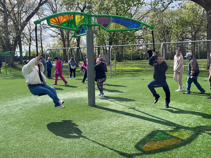 Attendees at a ribbon-cutting ceremony enjoy a uniquely designed swing at the Inwood Park playground on Friday, May 1, 2026, in Joliet.