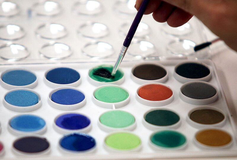 A woman dips her brush into the green paint in the craft area of Saturday's adults-only, after-hours party at the Barrington Area Library.