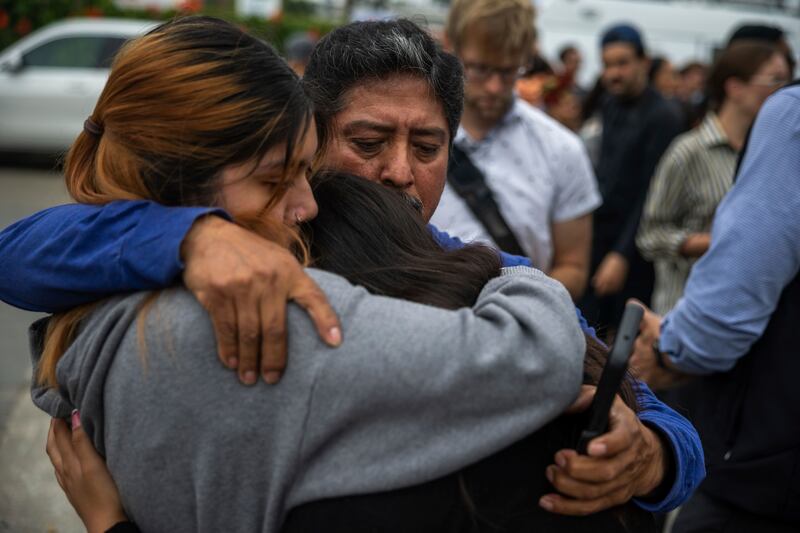 Jaslyn Hernandez, daughter of a car wash worker, embraces her sister Kimberly Hernandez, and their uncle Juan Medina during a press conference with families of detained car wash workers Wednesday, June 11, 2025, in Culver City, Calif. (AP Photo/Ethan Swope)