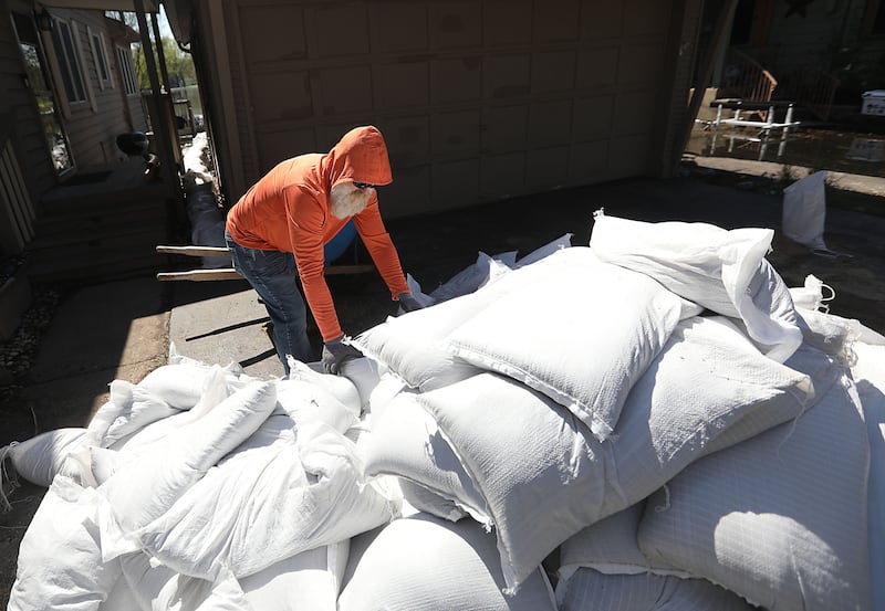 A volunteer loads sandbags into a wheelbarrow as he and  McHenry Home Depot volunteers work to protect a home as flooding continues on the Fox River on Wednesday, April 22, 2026, near Burton’s Bridge.