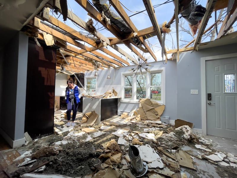 Emily LaVoie steps over debris in what was the kitchen at her Elmwood Drive home in Aroma Township on April 8, 2026. She and her husband, Dave Herberger, are in the process of planning repairs for the damage caused by the EF-3 tornado about one month ago.