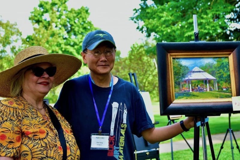 Chicago artist Don Yang (center) poses with event judge Bobbie Puttrich and his quick paint contest winning piece in Mt. St. Mary Park during the St. Charles Plein Air event in 2024.
