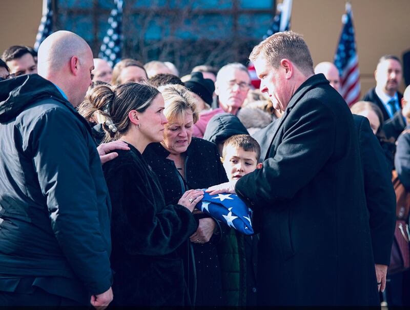 Illinois State Police Director Brendan Kelly hands a flag to Megan Carns, the widow of Trooper Clay Carns, who died on Dec. 23, 2024. John Fleet, 69, of Wilmington, was charged with violating Scott's Law.