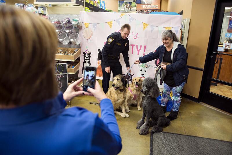 Elisa Gatz has her picture taken with Sterling Police Officer Jeff Mohr and Brinkley (center) during a party for the police Community Service Dog's third birthday Thursday. Gatz' two pets, Funky (left) and Pali also got in on the picture.