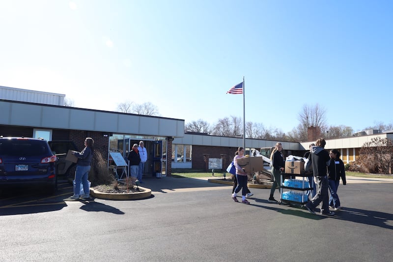 Volunteers help residents bring donations to their cars at Grace Christian Academy on Thursday, March 12, 2026.