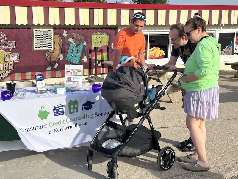 Payton and Taylor Gehm, along with 3-month-old Troy, chat with Jim Kearns of the Consumer Credit Counseling Service of Northern Illinois during a recent Project Popcorn night at the McHenry Outdoor Theater.
