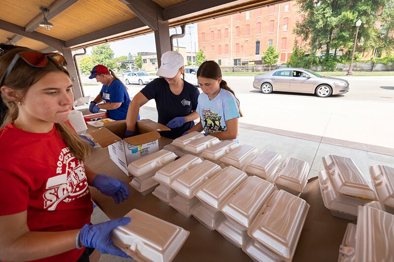 Brittany Whitman (left), working with the Impact Program at Sauk Valley Community College, volunteers Monday, July 24, 2023, at the Rotary Club’s Corn Boil and BBQ Pork Chop sale.