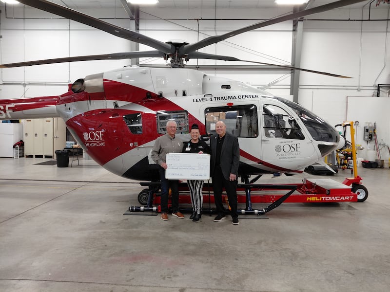 Members of the Utica Fireside White Sox Club present a ceremonial check to support the OSF HealthCare Foundation and the OSF Regional Emergency Medical Services Fund. Pictured from left are Randy Tuftie, president of the Utica Fireside White Sox Club; Bo Windy, club member; and Cherie Reynolds, development officer, OSF HealthCare Foundation. The $6,200 donation was recognized during a check presentation held March 31, 2026, at OSF Aviation in Peru.