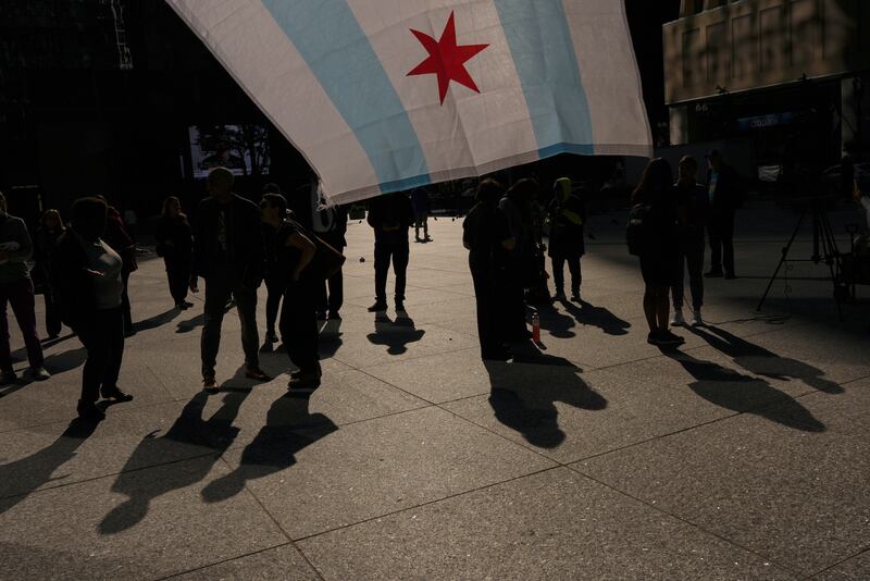 People hold a Chicago flag as they gather near Daley Plaza, Monday, Sept. 8, 2025, in Chicago. (AP Photo/Carolyn Kaster)