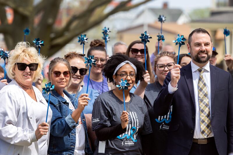 Approximately 100 people attend “Hands Around the Courthouse” Friday, April 25, 2025, to bring attention to Child Abuse Prevention Month. The blue pinwheel is a national symbol of child abuse prevention.