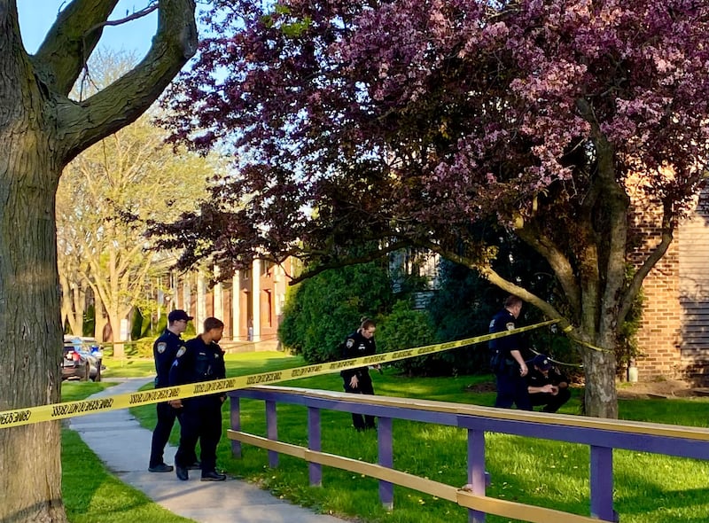 DeKalb police officers appear to search the ground for something on Monday evening, May 5, 2025, in an area outside an apartment building in the 900 block of Kimberly Drive, DeKalb. Police alerted the public to an ongoing investigation of possible gunfire in the area.