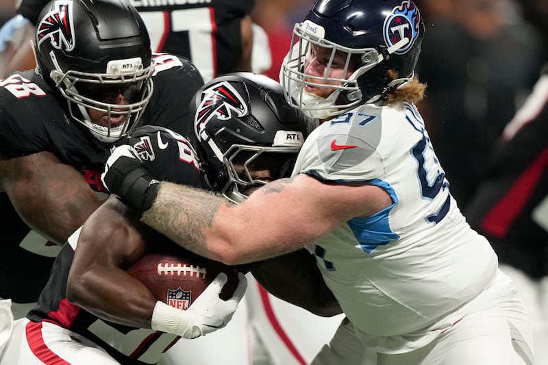 Tennessee Titans defensive lineman James Lynch, right, tackles Atlanta Falcons running back Nathan Carter (38) during the first half of a preseason NFL football game, Friday, Aug. 15, 2025, in Atlanta. (AP Photo/Brynn Anderson)