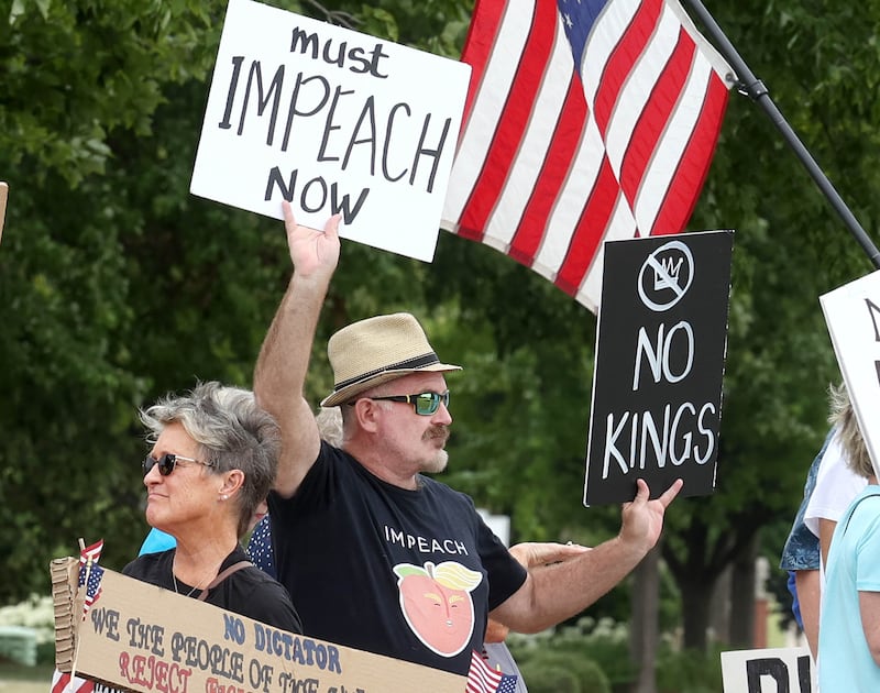 Protesters hold signs saying “Impeach,” and “No Kings,” Saturday, July 4, 2025, at the corner of Main and State Streets in front of the DeKalb County Courthouse in Sycamore for a "No Kings" rally to voice their displeasure with President Donald Trump.