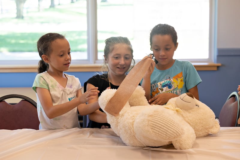 Kendra (left), Raegan and Bridget work together to wrap up a Teddy bear with tape Monday, July 28, 2025, during a workshop on the life of a veterinarian hosted by the University of Illinois Extension and the Whiteside 4-H club at the Rock Falls Library.