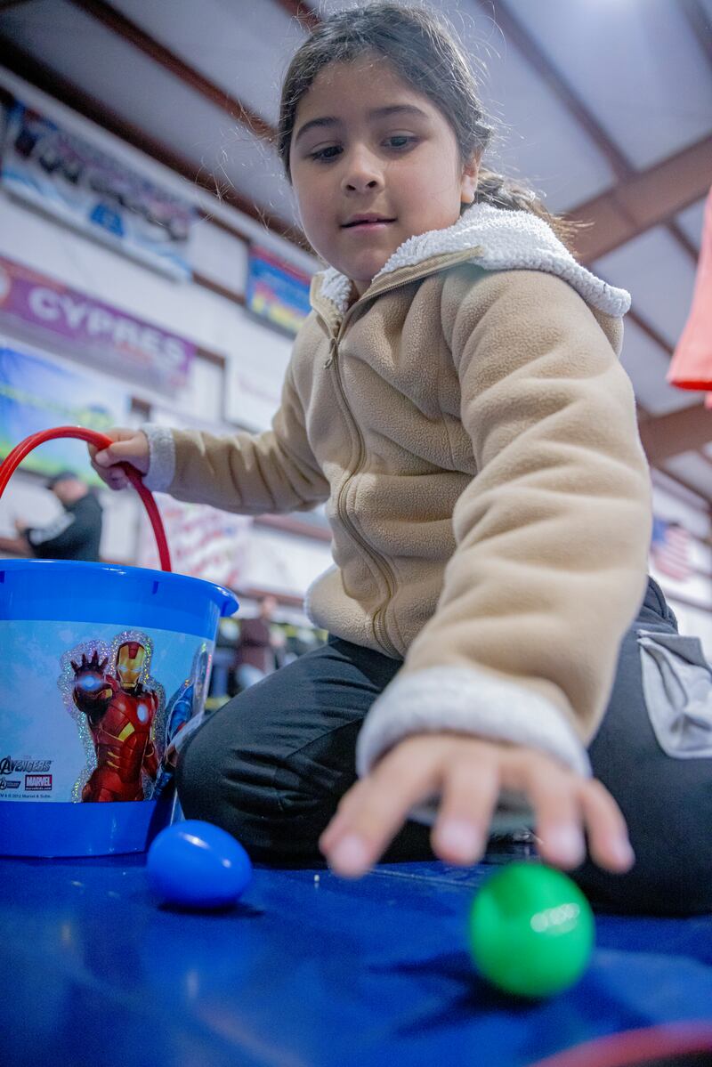 Jade Mumoz collects on of thousands of Easter eggs scattered around the hangar of Skydive Chicago on April 7, 2024. The eggs were divided up among different age groups for the kids safety.