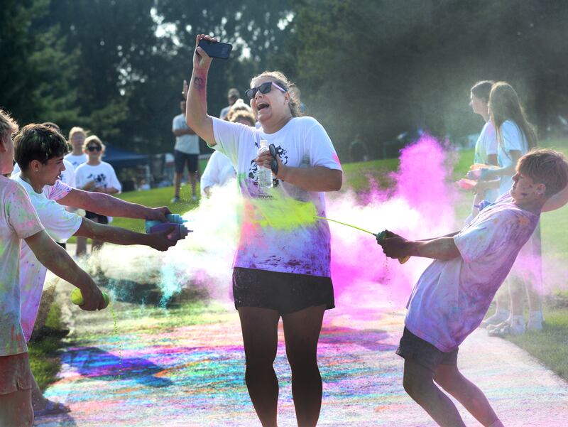 This runner tries to protect her phone as she runs through a powder station during the Oregon Park District's Color Run on Tuesday, July 22, 2025. The popular event had close to 400 participate at Park West.