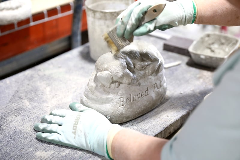 Deb Haggerty cleans up one of the pieces at Lion Concrete in Oswego. The shop, which was founded in 1925, is celebrating its 100th anniversary this year. The company, owned by Oswego couple Valerie and Scott Neupert, is now in its third generation.