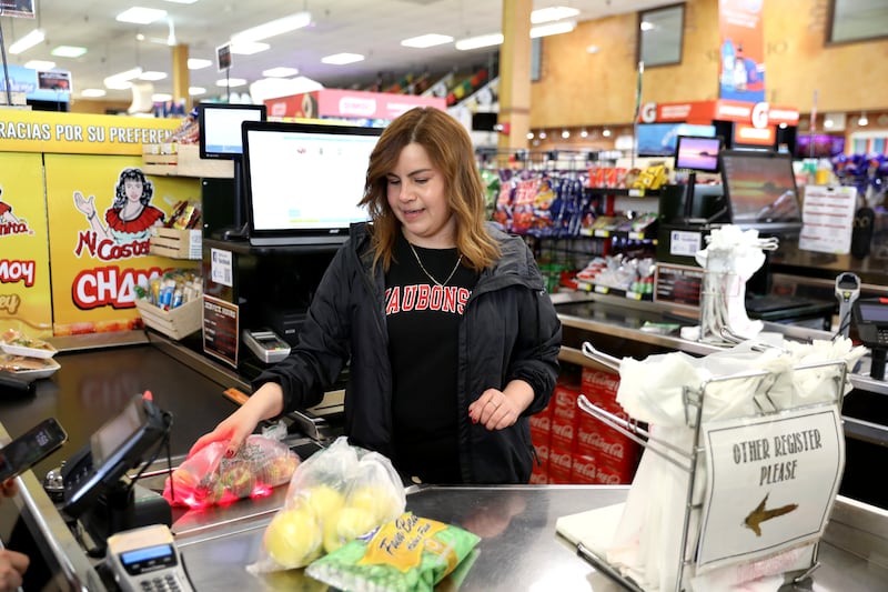 Rosie Abrejo scans items at the checkout at La Huerta Grill and Market in St. Charles.