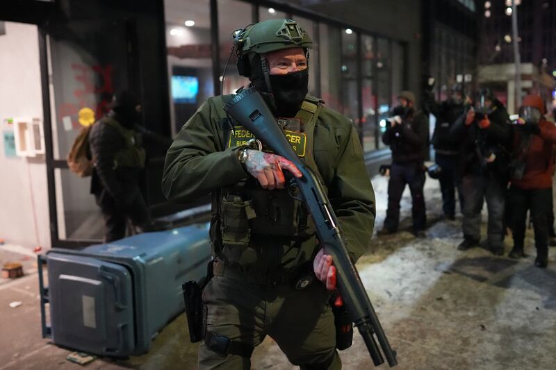 A federal agent stands guard near a hotel during a noise demonstration protest in response to federal immigration enforcement operations in the city Sunday, Jan. 25, 2026, in Minneapolis. (AP Photo/Adam Gray)