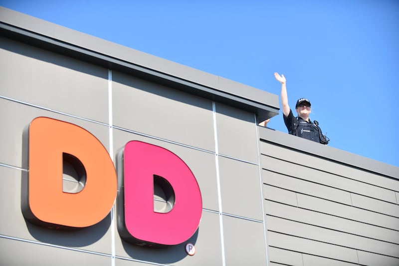 Manteno Police officer Karen Brandt waves from atop the Dunkin' in Manteno during the Cop on a Rooftop fundraiser to benefit Special Olympics Illinois in 2022.