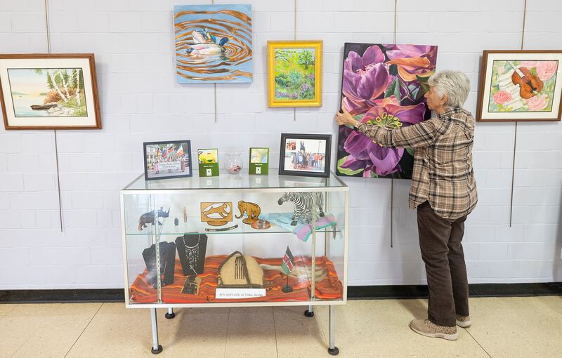 Rosemary Johnson hangs a work by local artist Karen Tucker Monday, March 31, 2025, at the Loveland House in Dixon for the 2025 Phidian Art Show.
