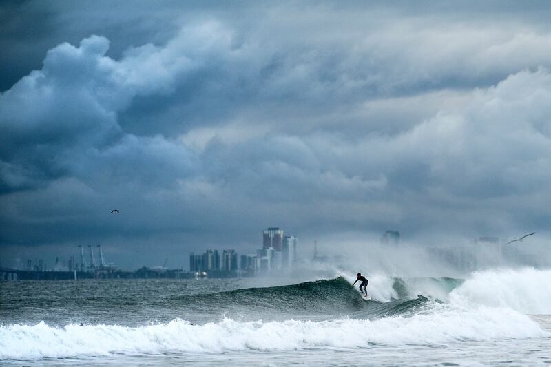 A surfer rides a wave as clouds gather above Bolsa Chica State Beach in Orange County, Calif., on Saturday, Nov. 15, 2025. (AP Photo/Noah Berger)