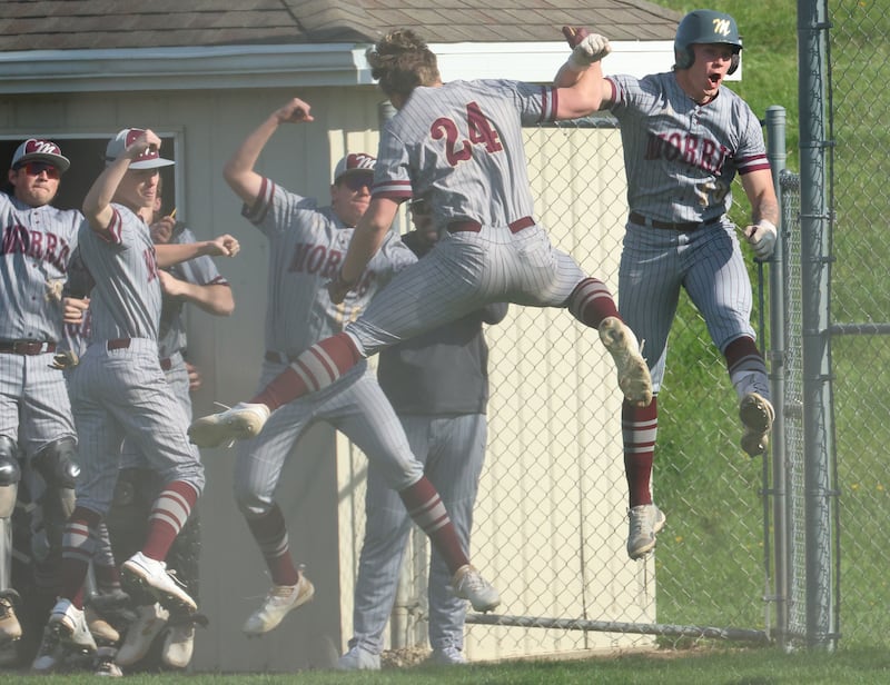 Morris' Carter Snyder (24) and teammate Mick Smith (far right) leap in the air in celebration of Snyder's three-run home run against Ottawa on Monday, April 20, 2026, at King Field in Ottawa.
