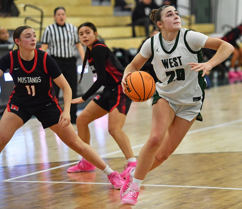 Glenbard West’s Ellie Noble (right) drives for a layup past Mundelein’s Casey Vyverman (11) and Gabby MacApinlac during a Grow the Game Showcase game on January 2, 2026 at Glenbard West High School in Glen Ellyn.