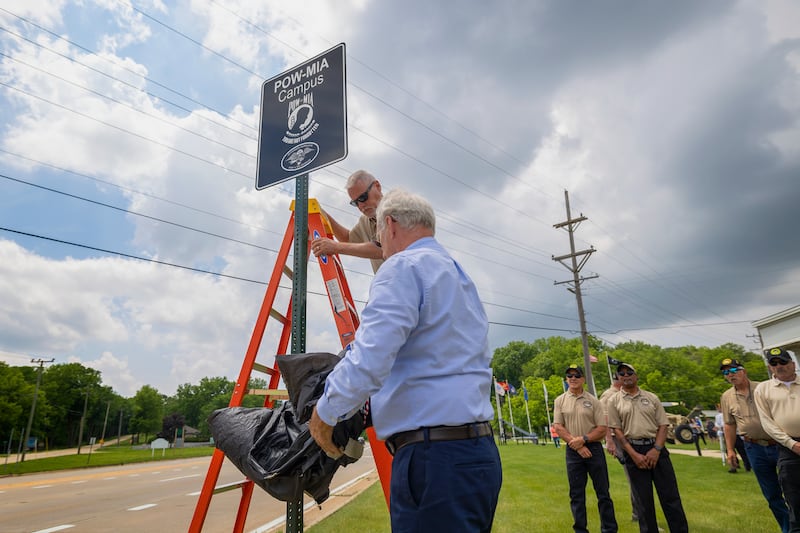 Veterans park commissioner Mark Allison (on ladder) and mayor Glen Hughes unveil new signage Sunday, June 8, 2025, officially marking Dixon as a POW-MIA city.