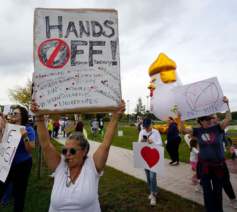 Francine Lombardo of Arlington Heights holds up her sign so drivers on Route 14 can see during the “No Kings” rally Saturday at Recreation Park in Arlington Heights.